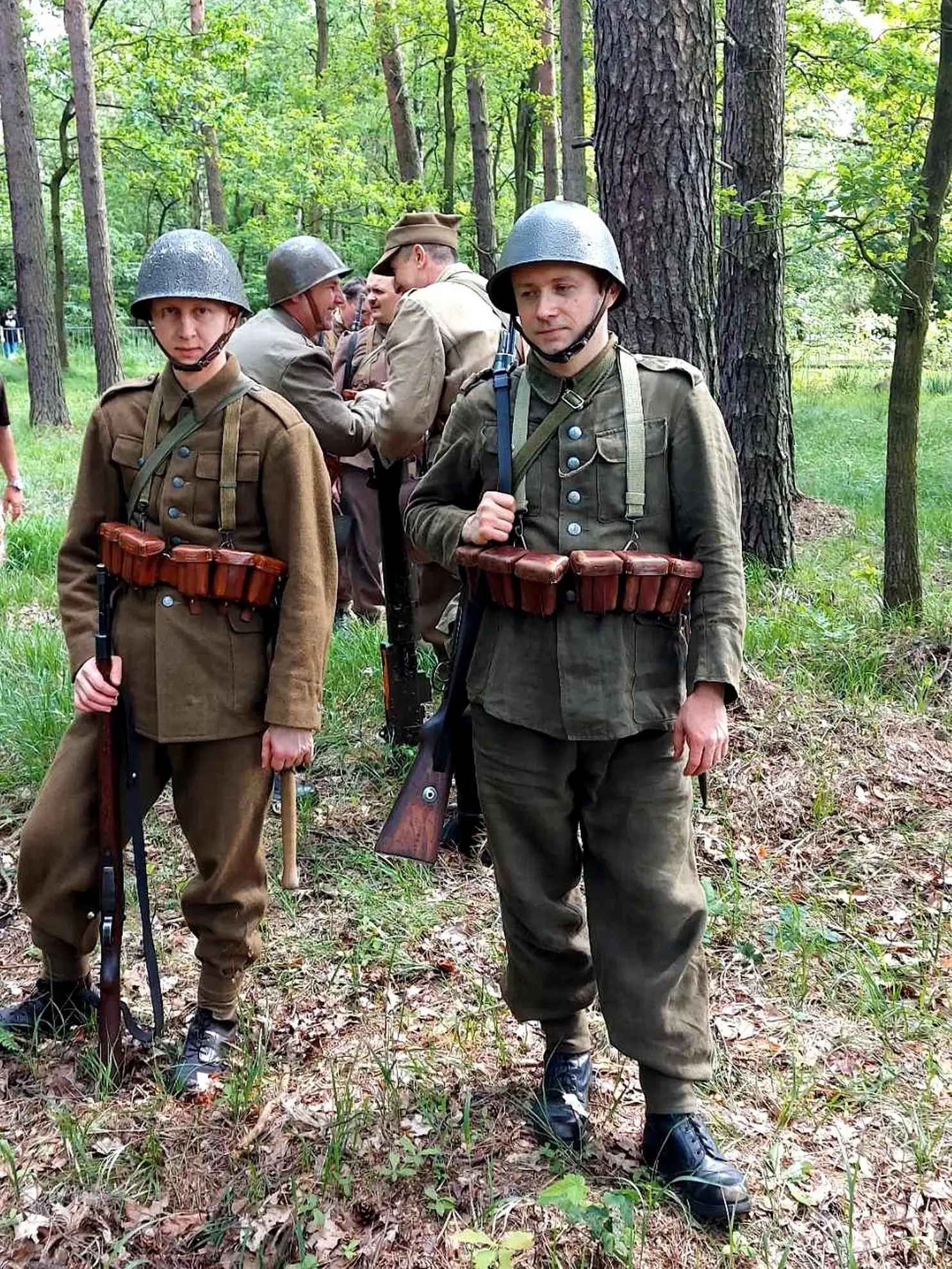 Rekonstruktorzy w historycznych mundurach w lesie